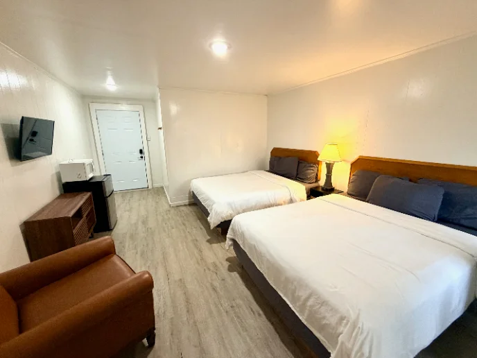 Room with two beds, an armchair and a microwave
